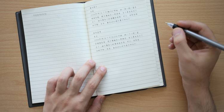 A writer studying a poem and counting syllables in a notebook