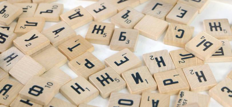 A creative scene showing open books with mirrored text and scrabble tiles spelling a palindrome, representing palindrome discovery and language games