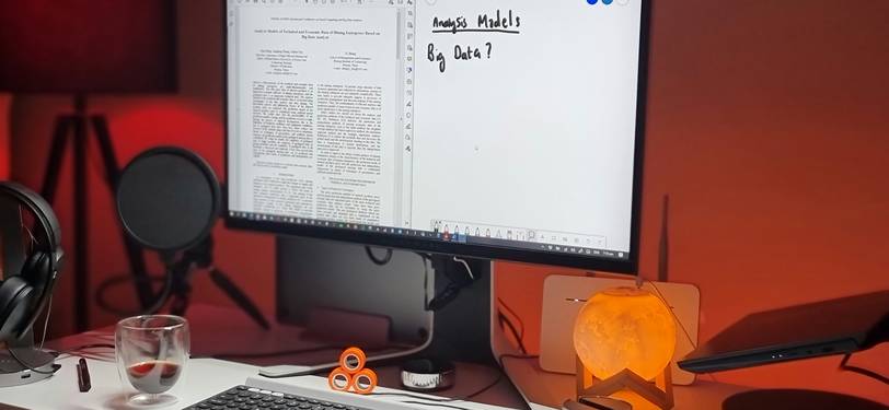 A person reviewing and editing text on a computer screen for readability and clarity, surrounded by writing tools in a modern workspace