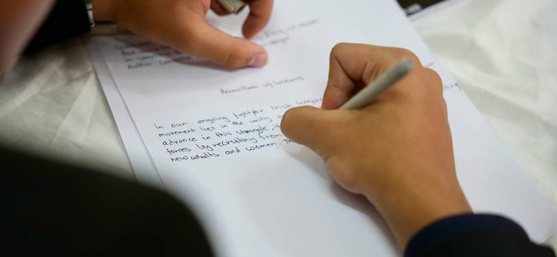 A focused writer editing a document to count sentences and improve clarity, using a notebook or digital device