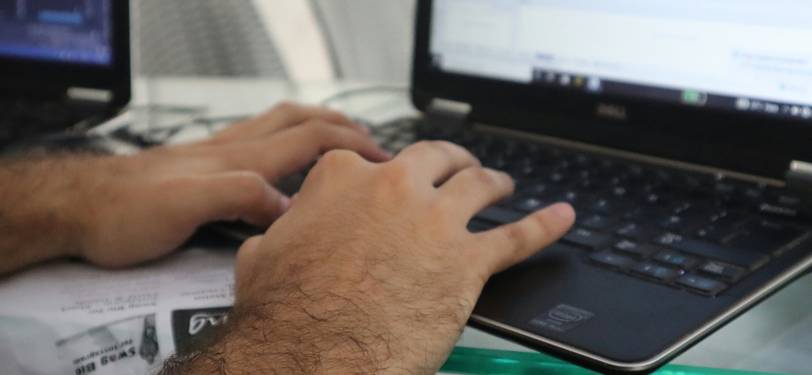 A writer or researcher analyzing word frequency data on a laptop, surrounded by printouts and notes, symbolizing digital content analysis and writing improvement